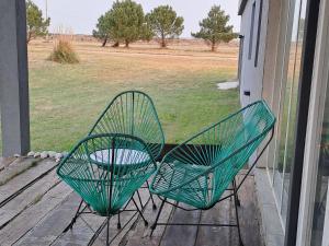 two green chairs sitting on a porch with a field at Sagastume in Las Toninas