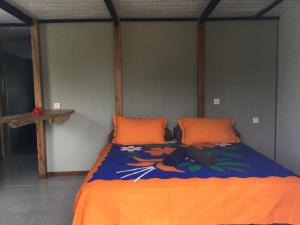 a bed with an orange blanket and orange pillows at Tubuai Fun Lodge in Tubuai
