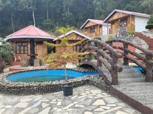 a bridge over a pool in front of a house at Dungmali Heritage Resort in Namchi