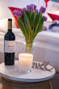 a table with a bottle of wine and a candle and flowers at SeaSide Sopot - butikowe noclegi przy plaży in Sopot
