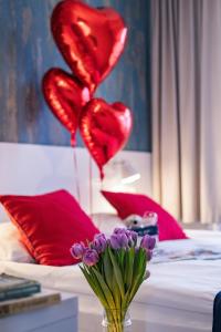 a vase with purple flowers and red heart balloons at SeaSide Sopot - butikowe noclegi przy plaży in Sopot