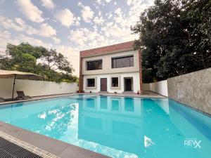 a swimming pool in front of a house at The Maple Woods Resort in Rāmnagar