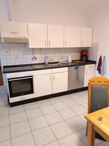 a kitchen with white cabinets and a stove top oven at Gästehaus Atrico Haus 76 in Surwold