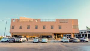 a building with cars parked in a parking lot at Aram Hotel - AlMeshael Exit 18 in Riyadh
