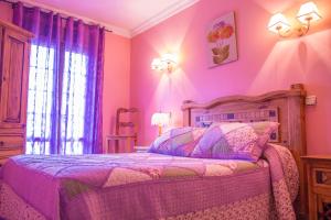 a bedroom with a bed with pink walls and a window at Hosteria Los Laureles in Noja