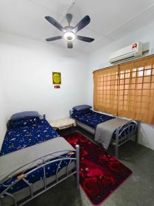 a bedroom with two beds and a ceiling fan at Orchid Homestay Pasir Gudang in Pasir Gudang