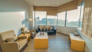 a living room with couches and tables and windows at Aram Hotel - AlMeshael Exit 18 in Riyadh
