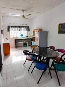 a room with a table and chairs and a kitchen at Orchid Homestay Pasir Gudang in Pasir Gudang +3 photos
