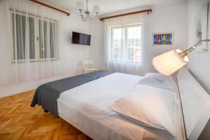 a bedroom with a large white bed and a lamp at Apartment House Zdrelac - Meri in Ždrelac
