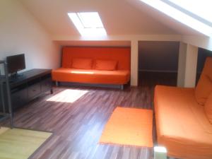 an attic room with an orange bed and a television at Wellapartman in Zamárdi