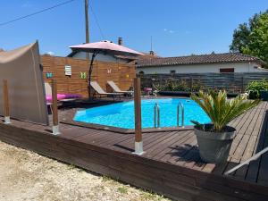 Saint-Médard-de-GuizièresにあるChambre zenの木製デッキ付きの裏庭のスイミングプール