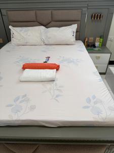 a bed with a white bedspread with flowers on it at MASAI Apartment Goba in Dar es Salaam
