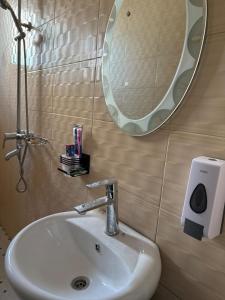 a bathroom sink with a mirror and a soap dispenser at MASAI Apartment Goba in Dar es Salaam