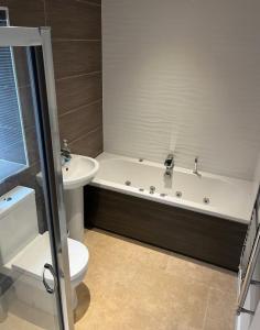a bathroom with a tub and a toilet and a sink at Plough Cottage in Bradfield