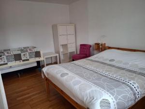 a bedroom with a bed and a pink chair at NORDIQUES DE LA WELCHE in Orbey