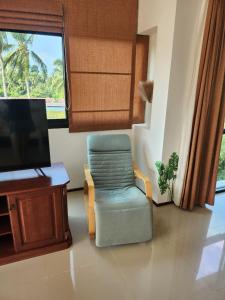 a living room with a chair and a television at Apartment in Koh Samui