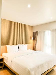 a bedroom with a large white bed and a window at Bangkok Mystay Hotel Rangsit in Thanya Buri