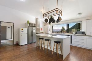 a kitchen with white cabinets and a large island with bar stools at Closeburn LakeView House in Queenstown