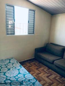 Cette petite chambre comprend un canapé et une fenêtre. dans l'établissement Sobrado com Piscina Oliveira, à Mongaguá