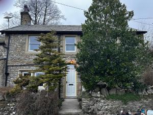 un cottage en pierre avec une porte blanche dans l'établissement Prior Hall Farm Cottage - 3 bedroom luxury cottage in center of Malham, à Malham