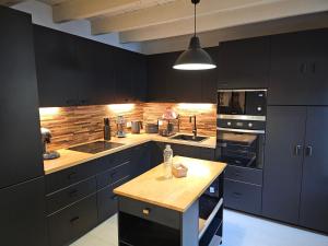 a kitchen with black cabinets and a wooden counter top at La charmante in Puyoô +12 photos