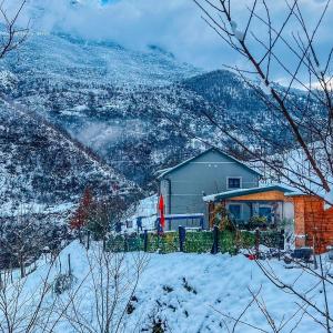 a house in the snow with mountains in the background at Te baca Qerim in Lekbibaj
