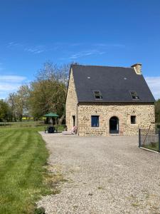 a stone house with a black roof on a gravel driveway at Charmant Gîte dans la Baie du Mont Saint-Michel in Pontorson