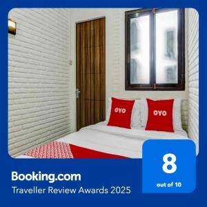 a bedroom with a bed with red pillows and a window at Hotel O Ara Guest House in Batu