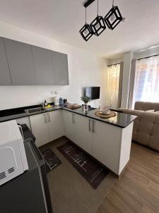 a kitchen with white cabinets and a living room at Spacious studio Ruaka in Ruaka +23 photos