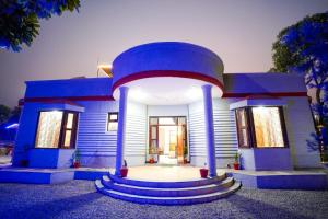 una casa azul con un patio delantero circular en Aravali Hills 6 BHK Farmstay By Lime Tree with Pvt Pool & Garden, en Gurgaon