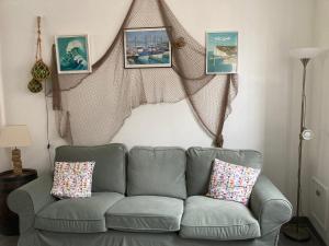 a couch in a living room with pictures on the wall at Chez Tipoulot - maison de pêcheur à 2 pas du port in Fécamp +19 photos