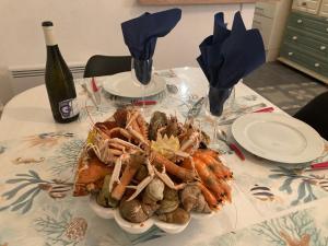 a table with a plate of seafood and a bottle of wine at Chez Tipoulot - maison de pêcheur à 2 pas du port in Fécamp