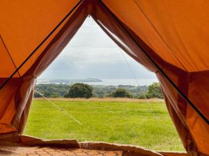 an orange tent with a view of a field at Boscoppa Farm-Furnished Bell Tent 4 in St Austell +11 photos