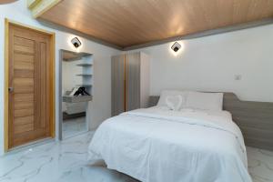 a bedroom with a white bed with a wooden ceiling at La Liviera in Ukulhas