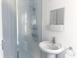 ein weißes Badezimmer mit Waschbecken und Dusche in der Unterkunft Spacious 5 Bedroom Gem Near Town Center, WiFi, Smart TVs, 2 Shower Rooms in Northampton + 17 Fotos
