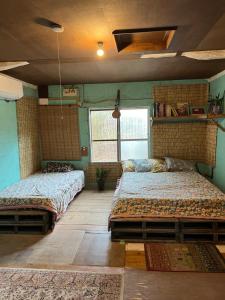 竹富岛Maison Paradis -Taketomi Island- メゾンパラディ竹富島的有两张床和一扇窗户的房间 更多34张照片