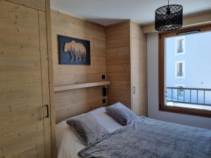 una camera da letto con pareti in legno e un letto con finestra di Apartment 70 m2 - 3 rooms - 6 people - ski-in ski-out a LʼAlpe-dʼHuez Altre 26 foto