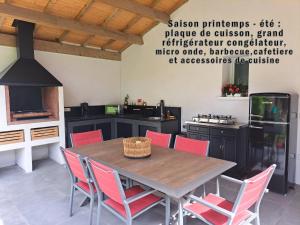 une cuisine avec une table en bois et des chaises rouges dans l'établissement Chambre d hôte la rivière 45m2 jardin et piscine, à Aigrefeuille-dʼAunis