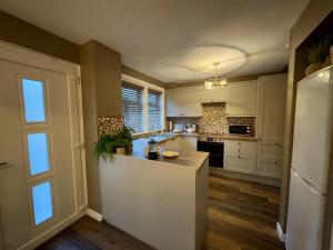 a kitchen with white cabinets and a white refrigerator at Cochrane House in Stirling