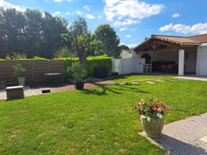 une cour avec un jardin fleuri dans un vase dans l'établissement Chambre d hôte la rivière 45m2 jardin et piscine, à Aigrefeuille-dʼAunis