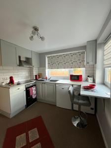 a kitchen with white cabinets and a table with a chair at Quest Fulfiller - Near General Hospital, Free Parking & Garden in Southampton +14 photos