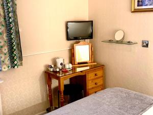 a bedroom with a desk with a television and a bed at Woodlea in Perth