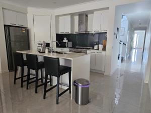 a kitchen with a island with black chairs in it at Bayside Home in Highett
