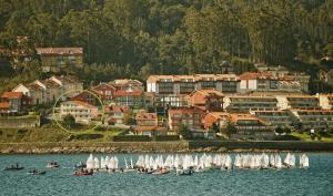 a group of boats with white sails in the water at Apartamento Playa de Quenxe in Corcubión