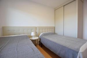 a bedroom with two beds and a table with a lamp at Apartamento Playa de Quenxe in Corcubión