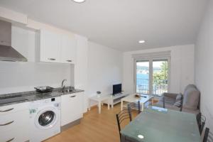 a kitchen and a living room with a table and a laundry machine at Apartamento Playa de Quenxe in Corcubión