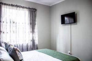 a bedroom with a bed and a television on a wall at Earthy Inn in Pretoria