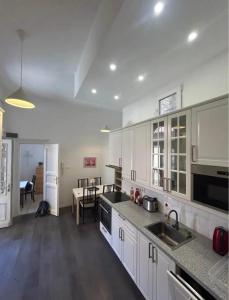 a kitchen with white cabinets and a sink and a table at Leo Heart Rooms in Budapest
