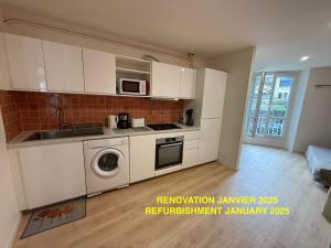 a kitchen with white cabinets and a washer and sink at Les Appartements Chambon in Sarlat-la-Canéda