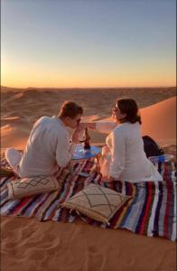 a man and woman sitting at a table in the desert at Merzouga Lovely Luxury Camp in Merzouga